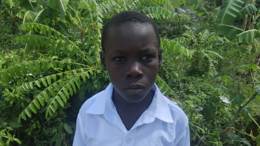 Boy in Light Blue Shirt by Green Foliage